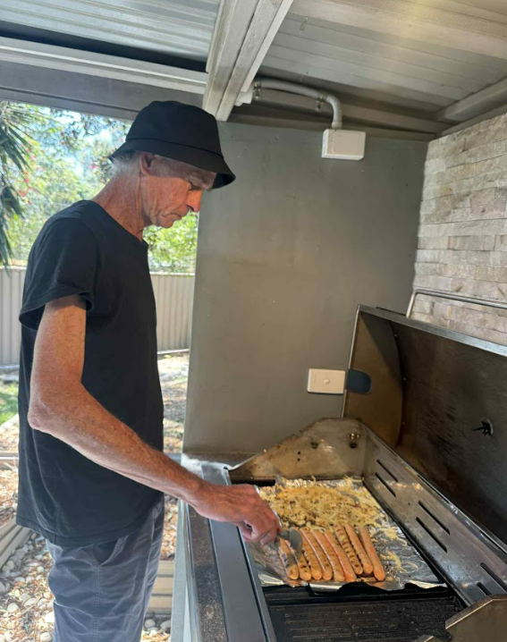 A resident cooking sausages on the BBQ