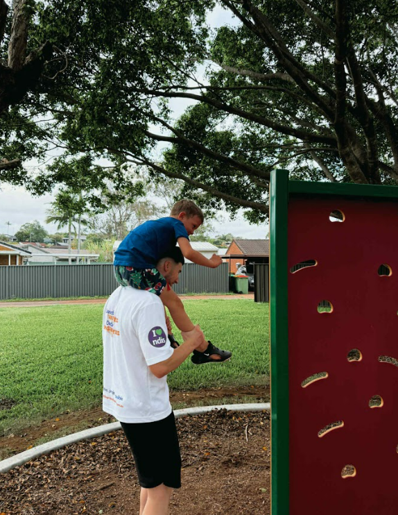 A support worker with a participant at a playground